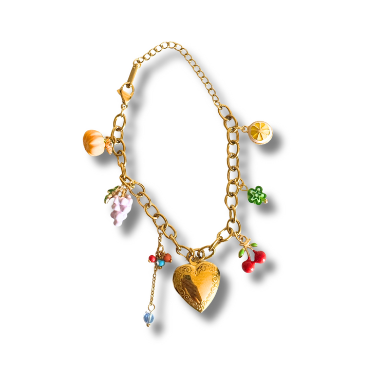 Gold bracelet with colorful charms on a white background.“Colorful fruit charm bracelet with heart locket, lemon, grapes, pumpkin, cherry and tassel – 18K gold filled”
“Summer charm bracelet featuring dainty fruit and floral charms with multicolor beads – hypoallergenic”