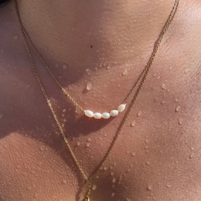  18-inch freshwater pearl necklace with gold accents, styled for a peaceful summer look.