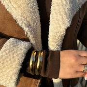 Close-up of adjustable 18k gold-filled double cuff bracelet on wrist, showcasing its shiny, sleek design and trendy layered look

