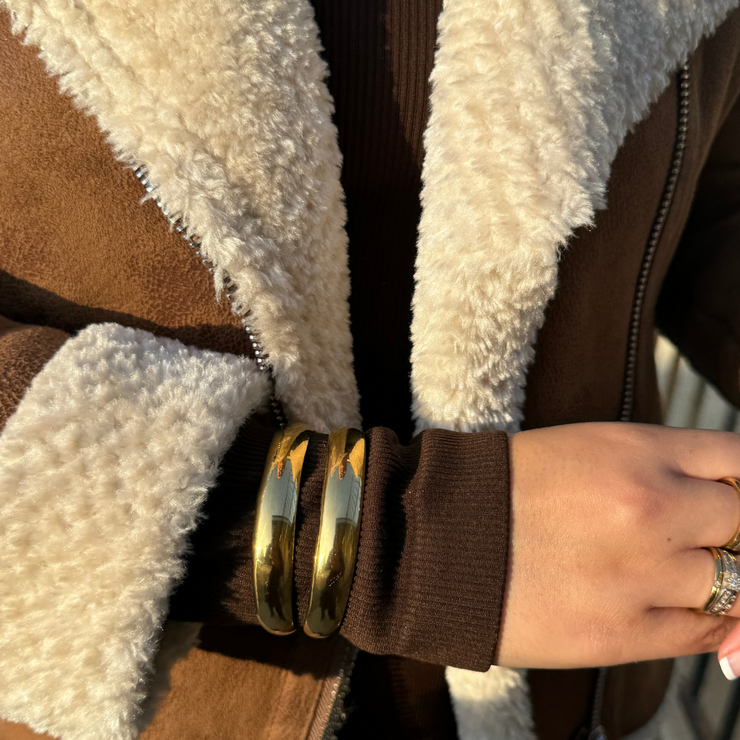 Close-up of adjustable 18k gold-filled double cuff bracelet on wrist, showcasing its shiny, sleek design and trendy layered look

