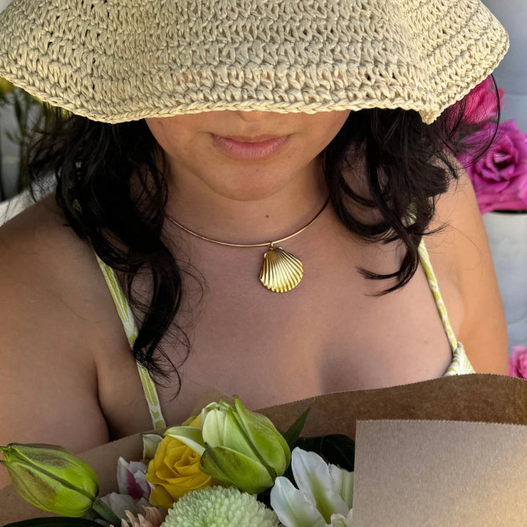 18k gold-filled wire choker necklace with a clam shell charm, styled at the base of the neck.