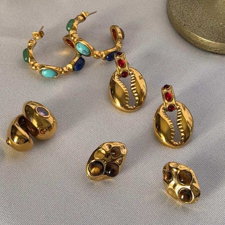 Gold earrings with gemstones on a light gray background .18k gold-filled hoop with green, teal, blue, and red gemstones; hypoallergenic, tarnish-free, waterproof fall statement hoop. 