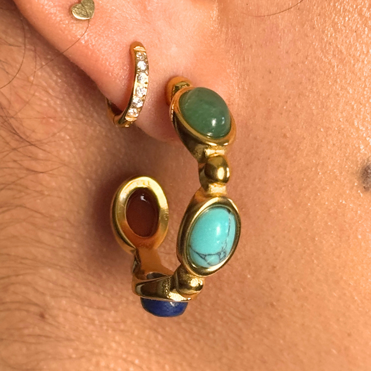 Gold hoop earrings with gemstones worn on an ear 18k gold-filled hoop with green, teal, blue, and red gemstones; hypoallergenic, tarnish-free, waterproof fall statement hoop.