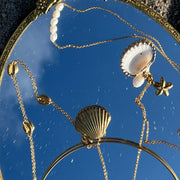 18k gold-filled wire choker necklace with a clam shell charm, styled at the base of the neck.