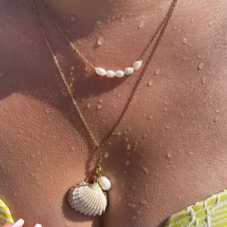 20-inch gold necklace with cockle shell, starfish, and pearl charms, styled on a breezy summer day.
