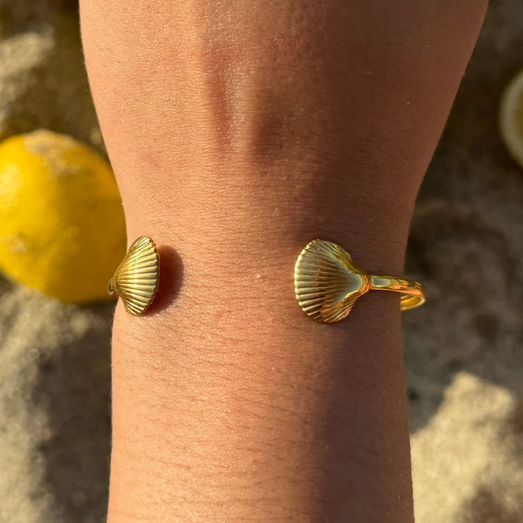 beach-ready open cuff with detailed sea shell ends that bring a coastal vibe to any look. Adjustable to fit most wrists. Crafted from waterproof, tarnish-free, 18k gold-plated material — perfect for daily wear.