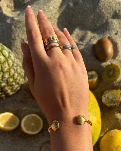 Adjustable gold cuff bracelet with sea shells on both ends.
