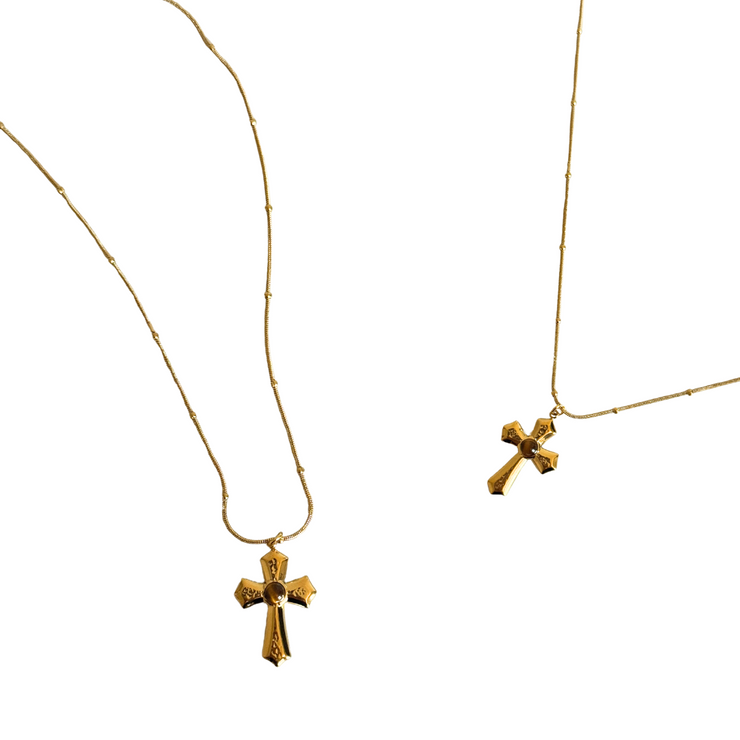 Two gold cross necklaces on a white background.Close-up of cross pendant with Tiger’s Eye gemstone set in gold-filled finish on a ball snake chain.