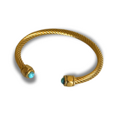 Gold bracelet with turquoise stones on a white background.Twisted 18k gold-filled open cuff on wrist with teal, brown, and green gemstone ends; adjustable, hypoallergenic design.