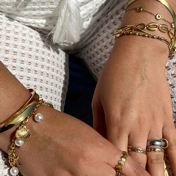 Bracelet with connected cowrie shells on a gold chain, perfect for summer beach looks.