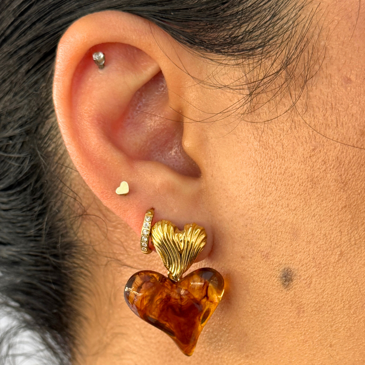 Two hearts, one mood. The top is a textured gold heart; below, a glossy amber-resin heart adds warm, honeyed glow. Sweet, romantic, and ultra-light for all-day wear.
