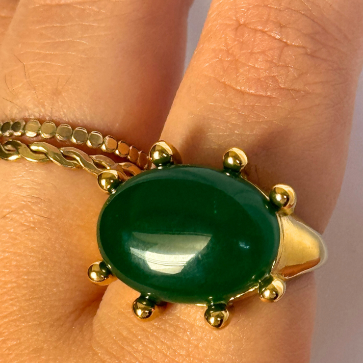 Gold ring with a green stone on a finger