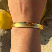 Medium gold cuff with a soft indent in the center, adjustable to fit most wrists.