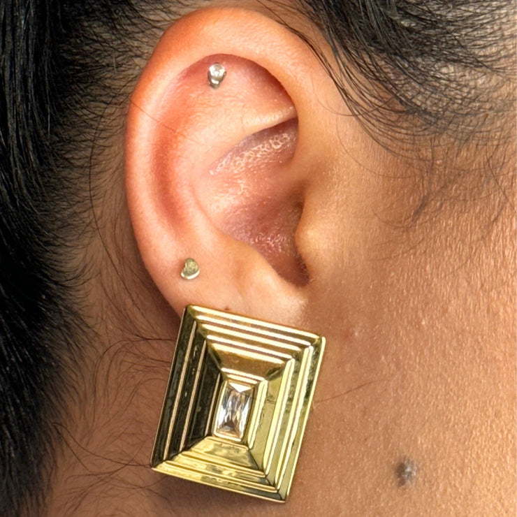 This isn’t your ordinary stud. The Luna Frame features a rectangular CZ at its center, surrounded by a silver and gold outline that adds depth and texture. A layered look without the layering — the perfect statement earring for turning heads effortlessly.