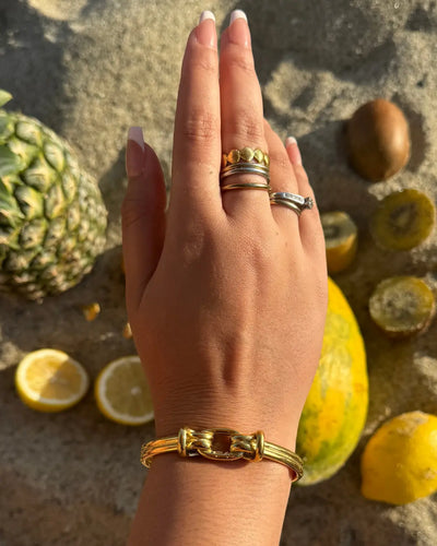 Adjustable gold cuff bracelet with a large center knot design.