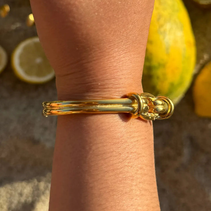 Adjustable gold cuff bracelet with a large center knot design.