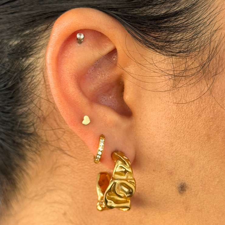 An organic, sculpted hoop that feels both natural and edgy. The hammered texture gives dimension without bulk, making it an easy everyday statement. 18k gold-filled, hypoallergenic, and tarnish-free.