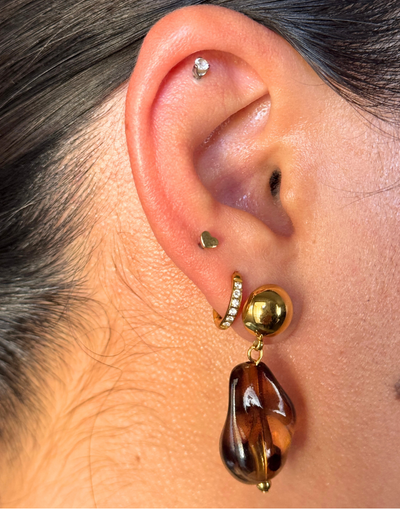 Close-up of an ear wearing a gold and brown earring. tortoise shell earrings, resin dangle earrings, earthy jewelry, statement drop earrings, holiday dangles, textured resin earrings.