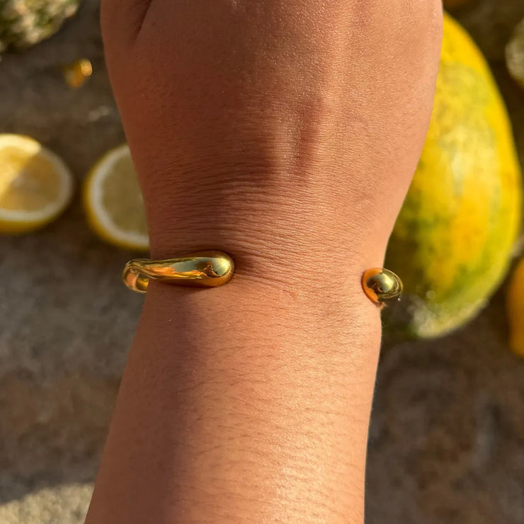 Gold wavy cuff bracelet with open space, designed to hug the wrist.