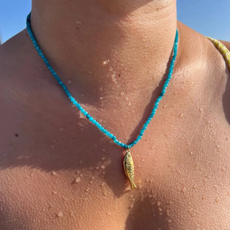 Blue beaded necklace with gold fish charm.