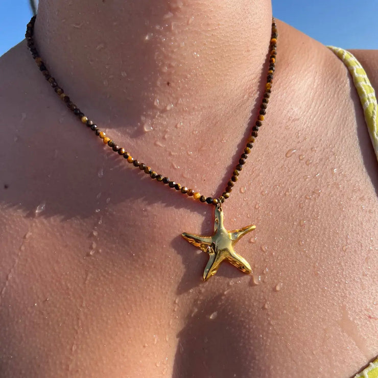 Brown beaded necklace with gold starfish charm.