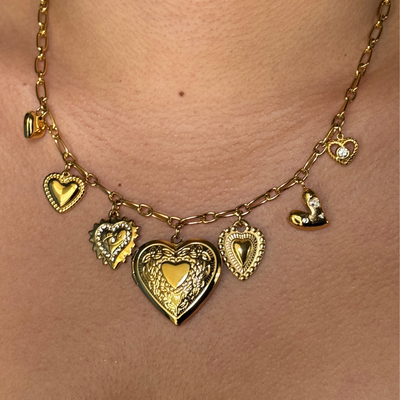 Statement heart locket charm necklace featuring a central locket and six unique heart charms, some plain and others with CZ stones. Hypoallergenic, tarnish-free, and perfect for keeping cherished memories close.