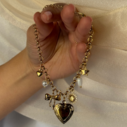  Adorable charm bracelet featuring a cute bow, heart charms, pearls, a sun, and a medium-sized heart locket to hold a cherished photo. Hypoallergenic, tarnish-free, and perfect for everyday wear.