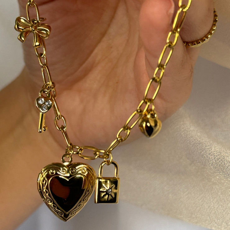 Elegant charm bracelet with a lock and key, bow, and heart locket to keep a treasured photo close. Hypoallergenic, tarnish-free, and a timeless accessory for any jewelry collection.