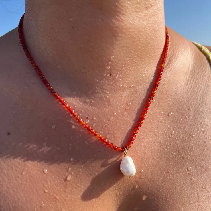 Red beaded necklace with pearl charm.