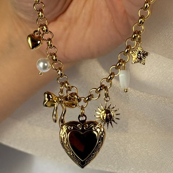  Adorable charm bracelet featuring a cute bow, heart charms, pearls, a sun, and a medium-sized heart locket to hold a cherished photo. Hypoallergenic, tarnish-free, and perfect for everyday wear.